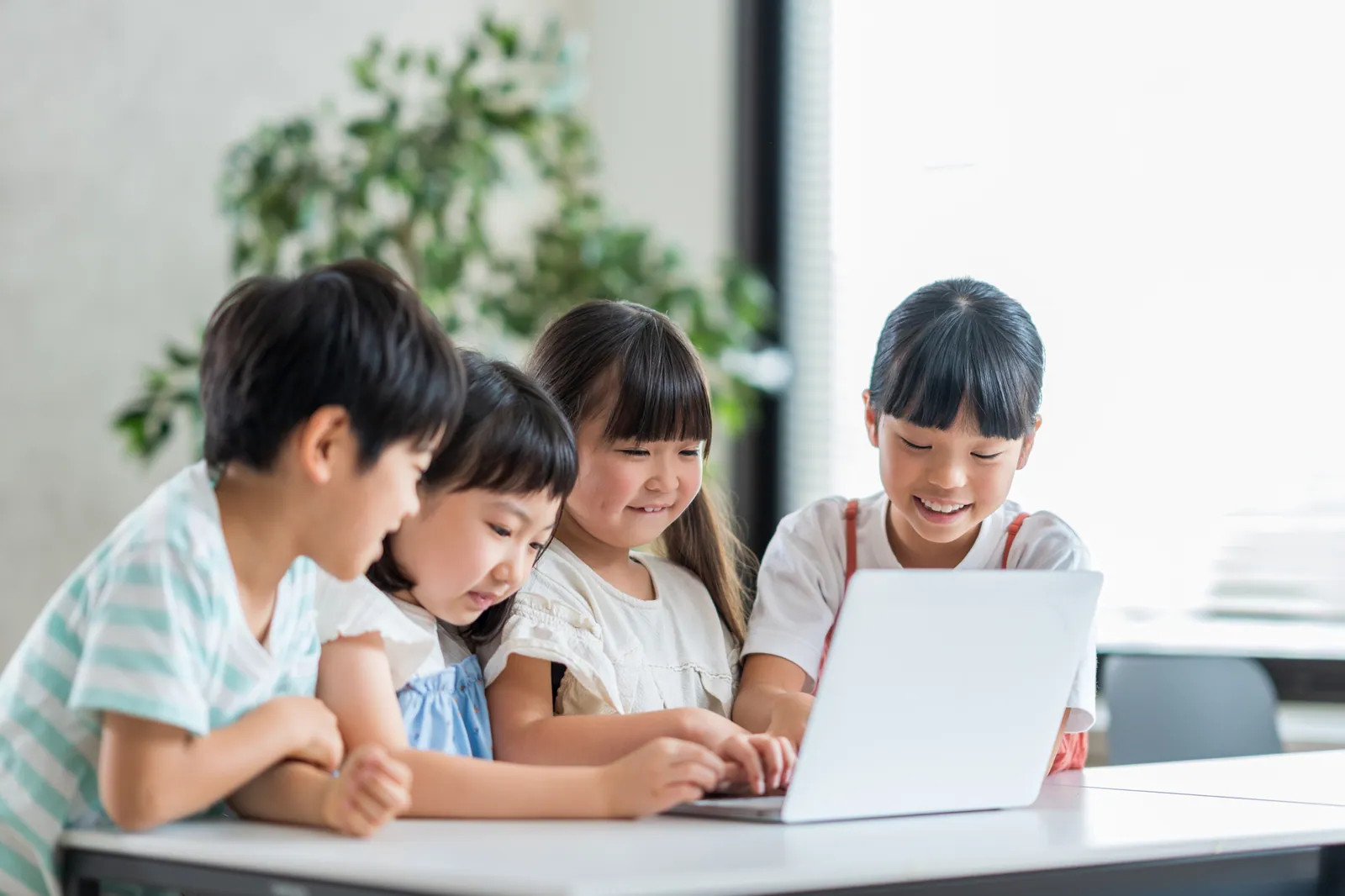 1台のノートパソコンを囲んで楽しそうに操作する子どもたち
